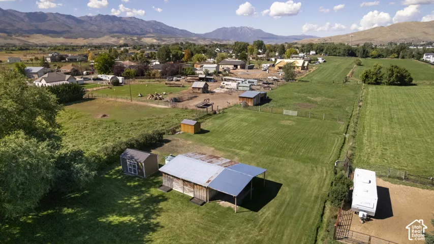 Expansive green fields, multiple outbuildings, mountain backdrop, and scattered mature trees