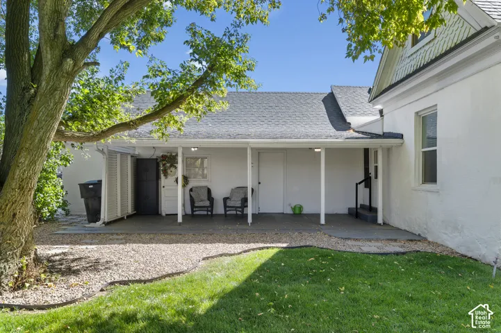 Covered patio with supporting columns, shingled roof, and a gravel-edged lawn