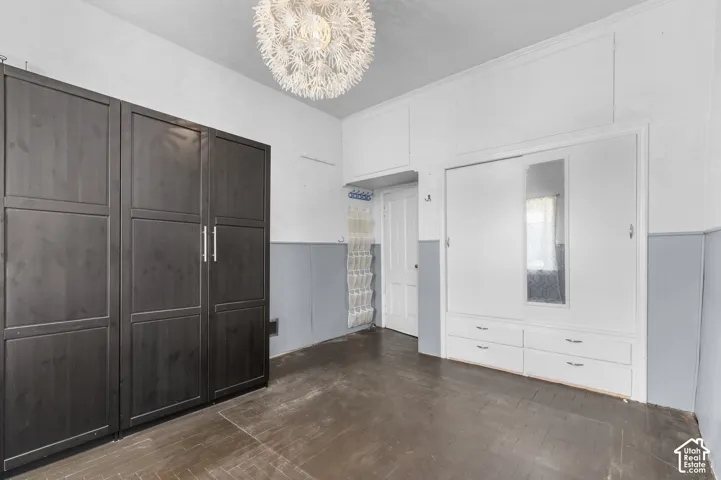 Wood-finish flooring, built-in storage cabinetry, white painted walls, and a decorative ceiling light fixture