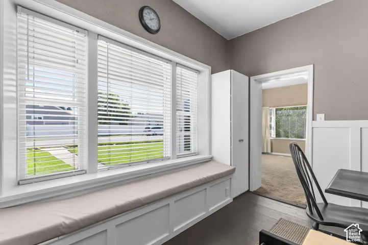 Built-in window bench with cushion, dark wood-finish flooring, and white paneled wainscoting