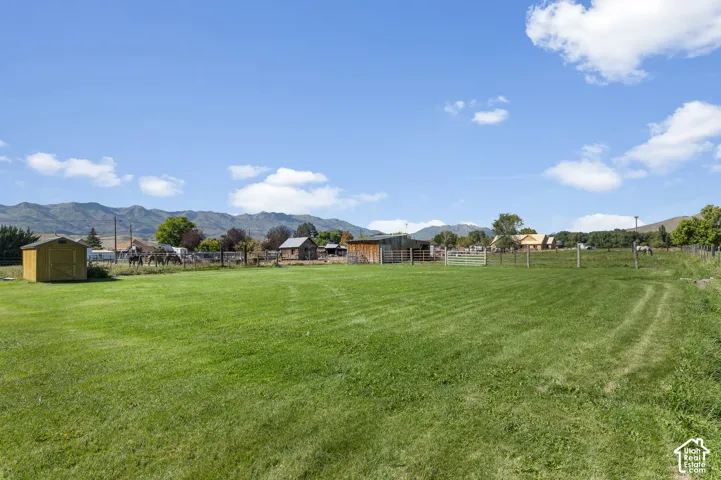 Expansive green field with mountain backdrop, shed, and distant outbuildings