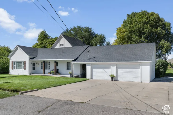 White brick exterior with a dark shingle roof, featuring a covered front porch with dark wood columns