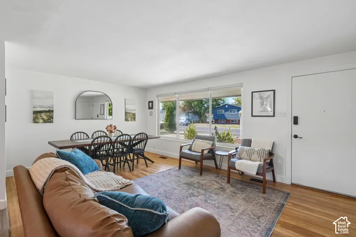 Hardwood-finish flooring, white painted walls, large picture windows, and a solid-core entry door with matte black hardware