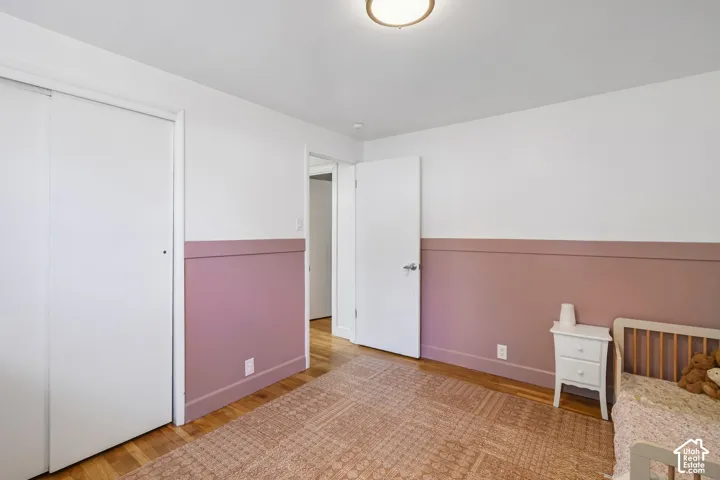 Hardwood flooring, painted walls with wainscoting detail, ceiling-mounted light fixture, and a white sliding closet door