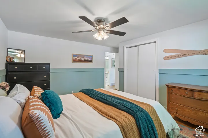 Ceiling fan with integrated lighting, sliding closet doors, and painted accent wall