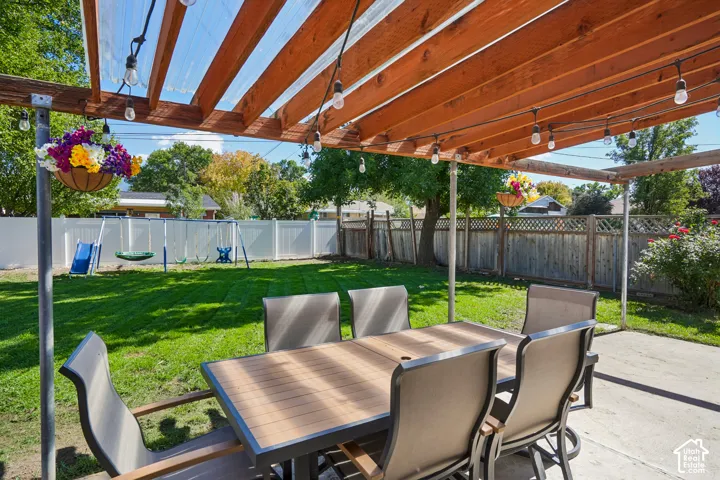 Concrete patio with a wood pergola, translucent panel roof, and string lighting