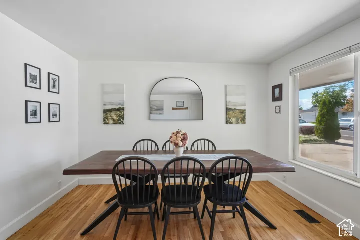 Hardwood flooring, arched wall mirror, and a large window with a white frame