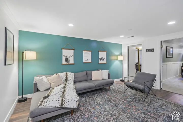 Accent wall with recessed ceiling lighting, wood-finish flooring, and white trim