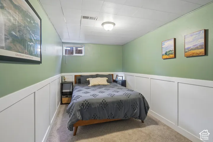 Wall-to-wall carpeting, wood-paneled bed frame, panel molding, and a flush mount ceiling light fixture
