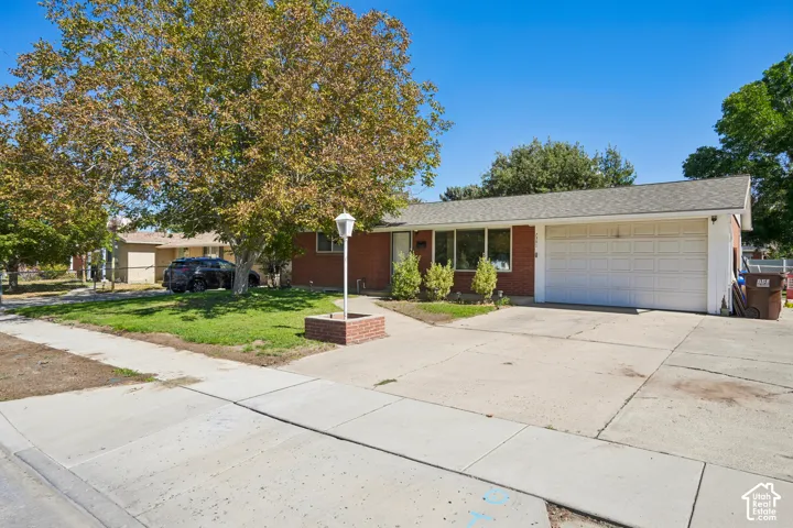 Brick exterior featuring a white garage door, large front windows, and a concrete driveway