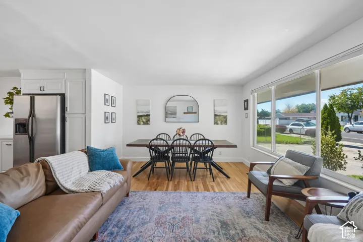 Hardwood flooring, expansive window, white cabinetry, stainless steel refrigerator, and recessed lighting