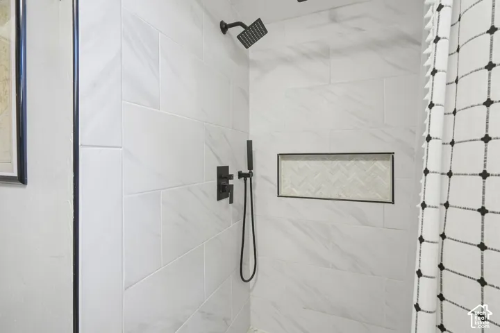 Shower enclosure with large format tile, matte black fixtures, and a recessed niche featuring herringbone tile