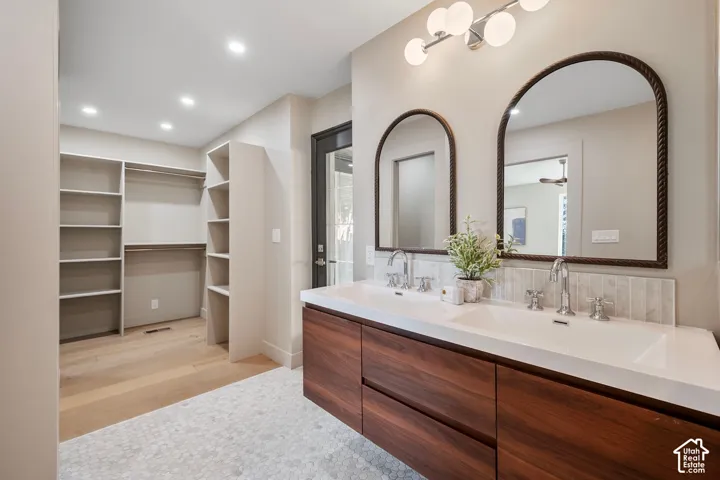 Dual arched mirrors with textured frames above a double vanity with wood-finish cabinetry