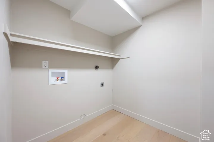 Laundry area featuring a built-in shelf, light wood-finish flooring, and a utility sink hookup