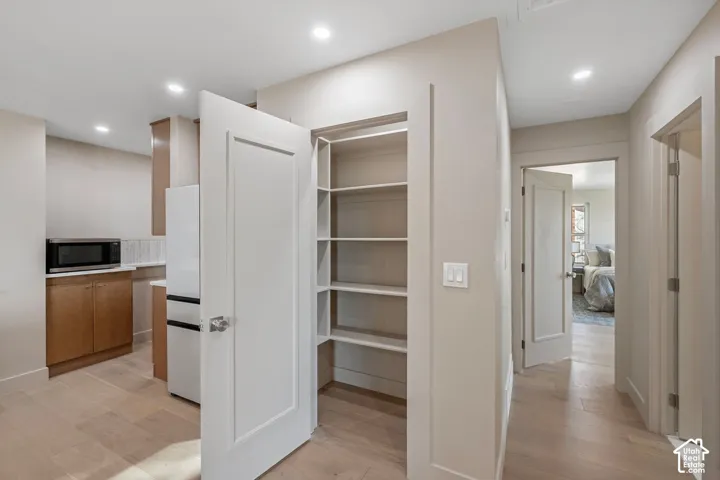 Recessed lighting, wood-finish flooring, built-in pantry shelving, kitchen area with wood-finish cabinetry, and a subway tile backsplash