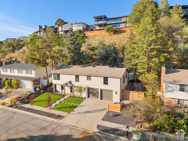 Contemporary-style exterior with a clean façade, dual garage doors, a covered entry, and a manicured front lawn