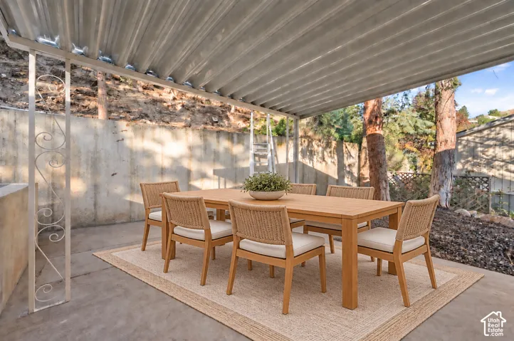 Covered outdoor patio with a corrugated roof, concrete flooring, and decorative metal support posts