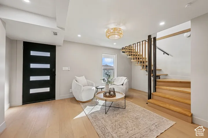 Recessed lighting, wood-finish flooring, and a modern chandelier illuminate the space