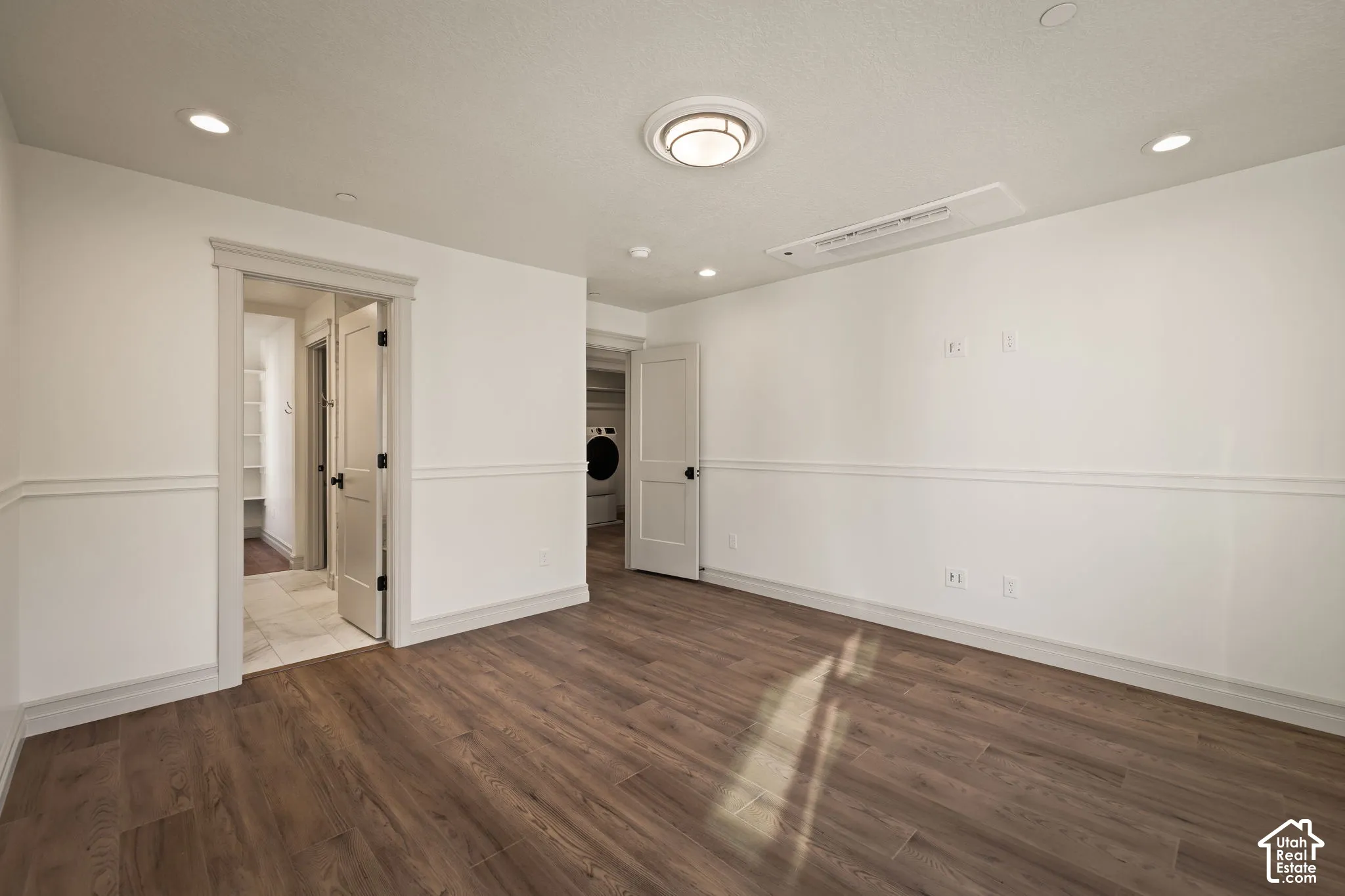 Wood-finish flooring, white walls with wainscoting, recessed lighting, and a flush-mount ceiling light