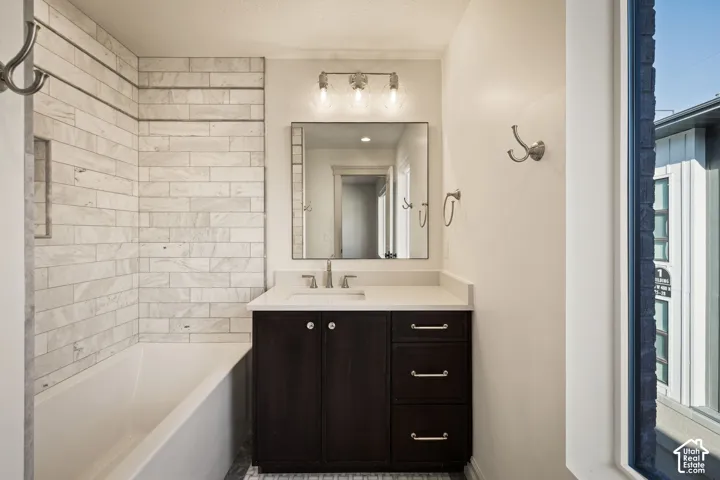 Bathroom featuring a white subway tile surround, dark wood-finish vanity, light-toned countertop, and mosaic tile flooring