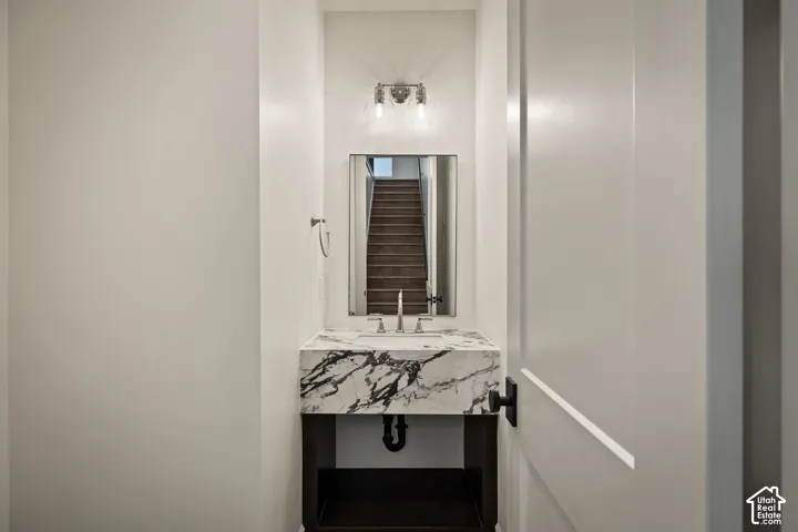 Floating vanity with a stone countertop, an undermount sink, and a wall-mounted mirror