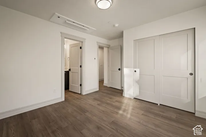 Wood-finish flooring with white walls, a semi-flush mount ceiling fixture, and a built-in closet with sliding panel doors