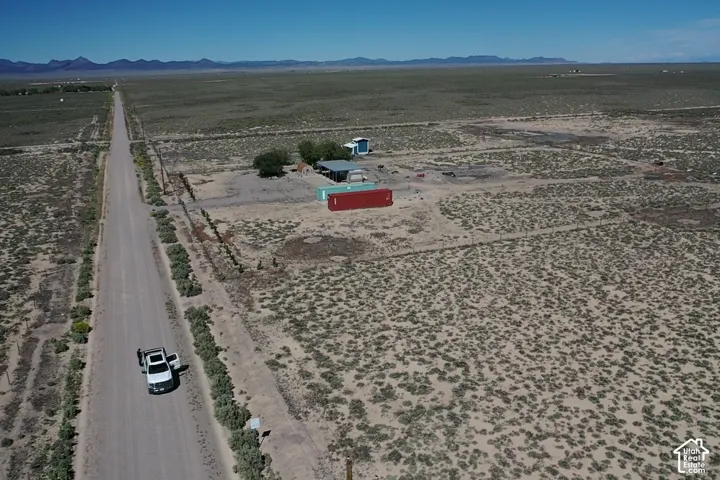 Expansive undeveloped land featuring a long dirt road and distant mountain ranges