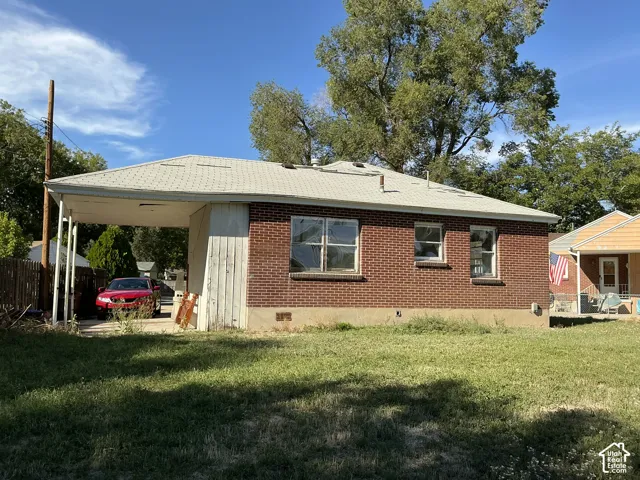 Brick exterior with multiple windows and an attached carport