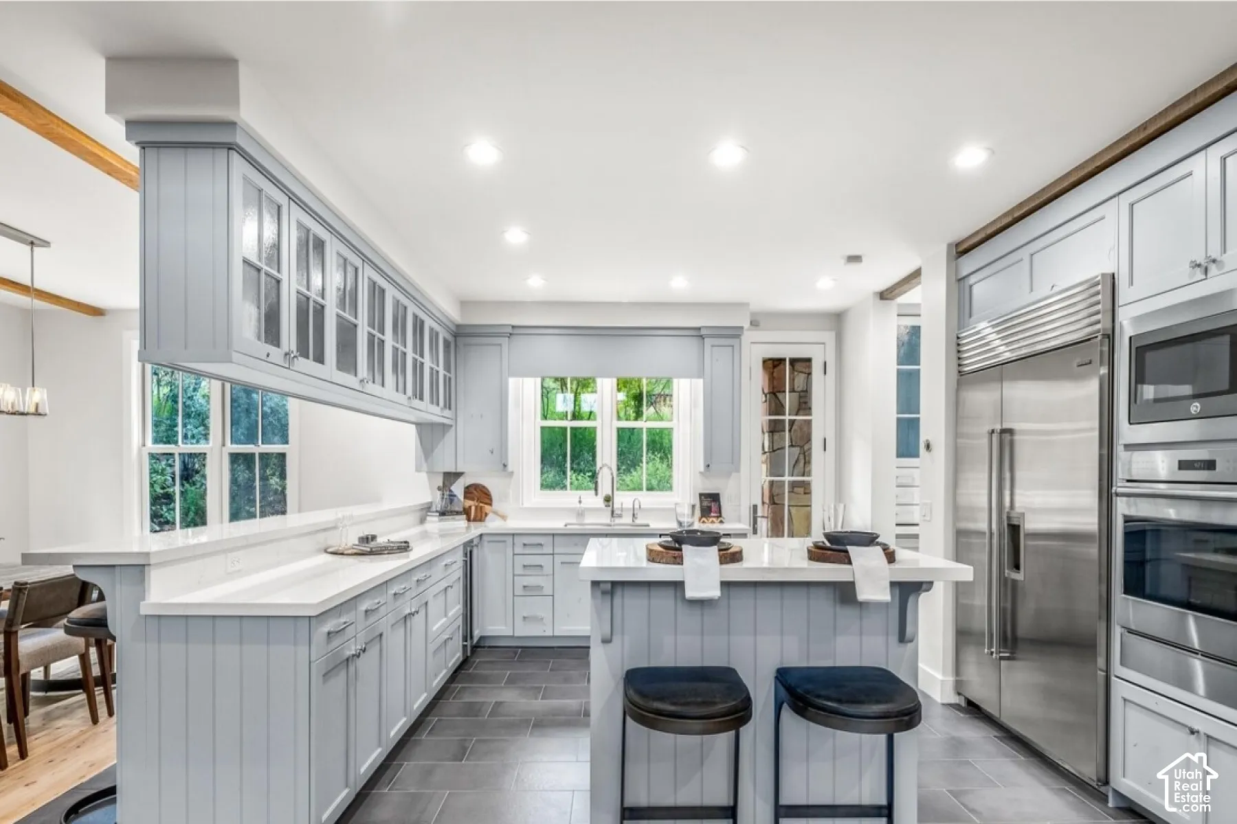 Expansive kitchen featuring light-toned cabinetry, white countertops, tile flooring, and stainless steel appliances