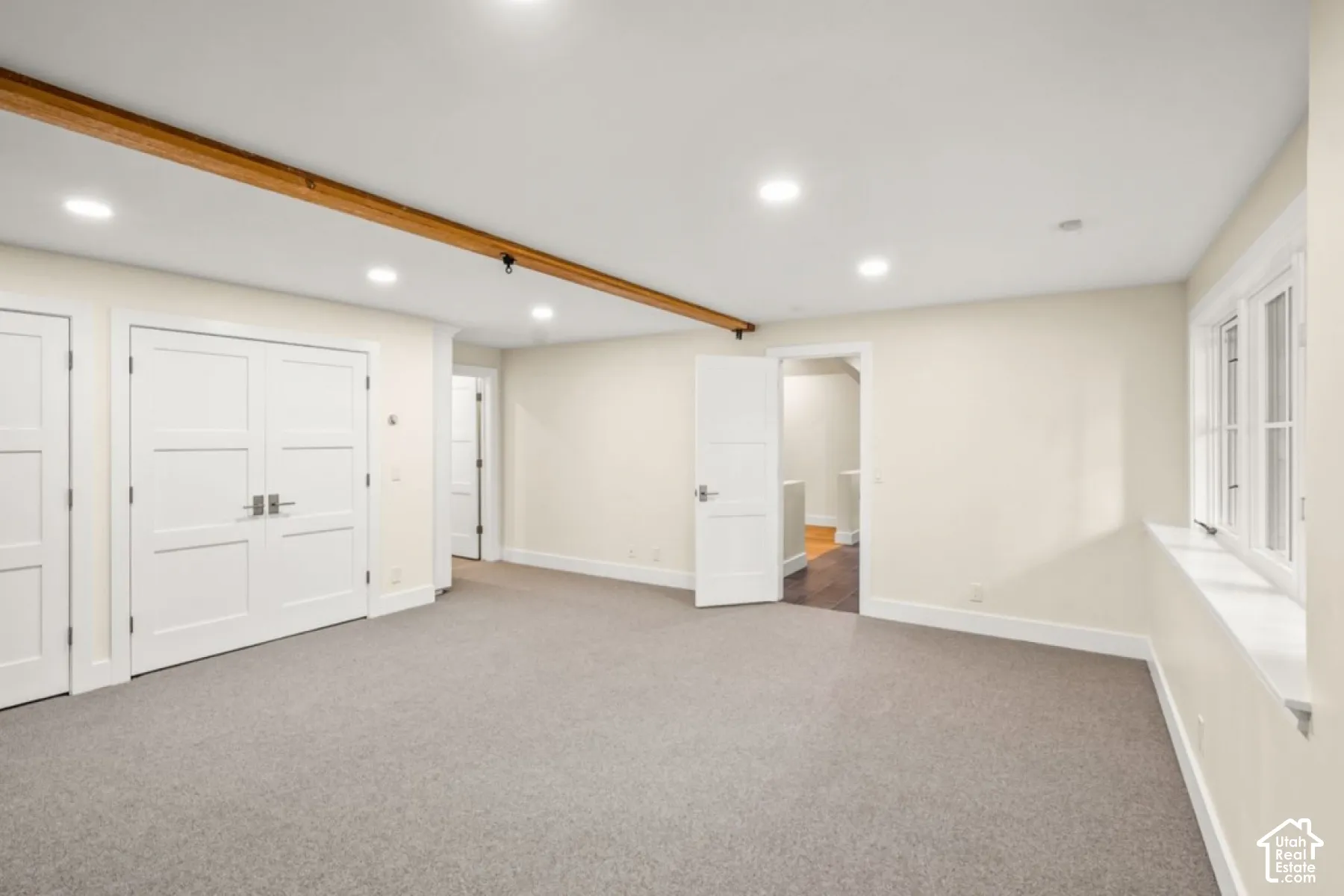 Recessed lighting, wood beam ceiling accent, neutral wall paint, gray carpet flooring, multiple panel doors