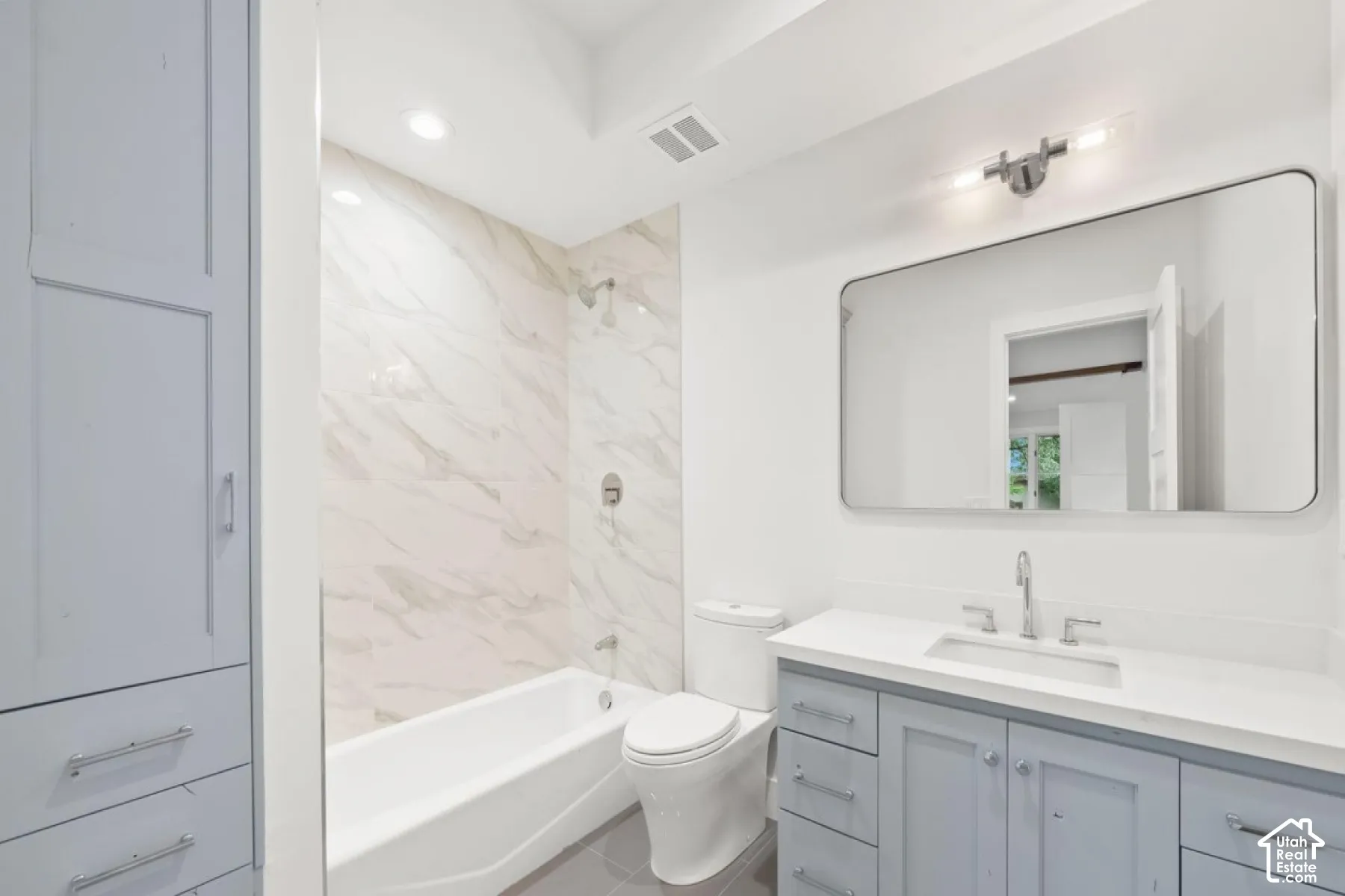 Bathroom with a light blue vanity, integrated sink, and white countertop