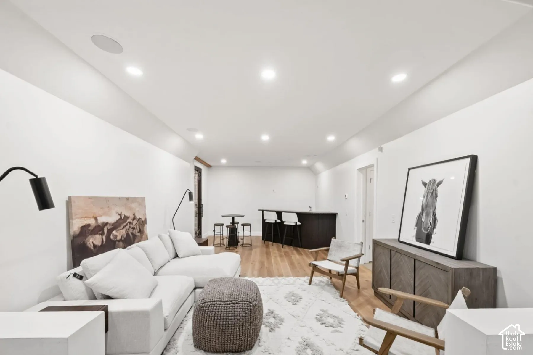 Recessed ceiling lighting, wood-finish flooring, built-in bar with dark cabinetry, and white walls