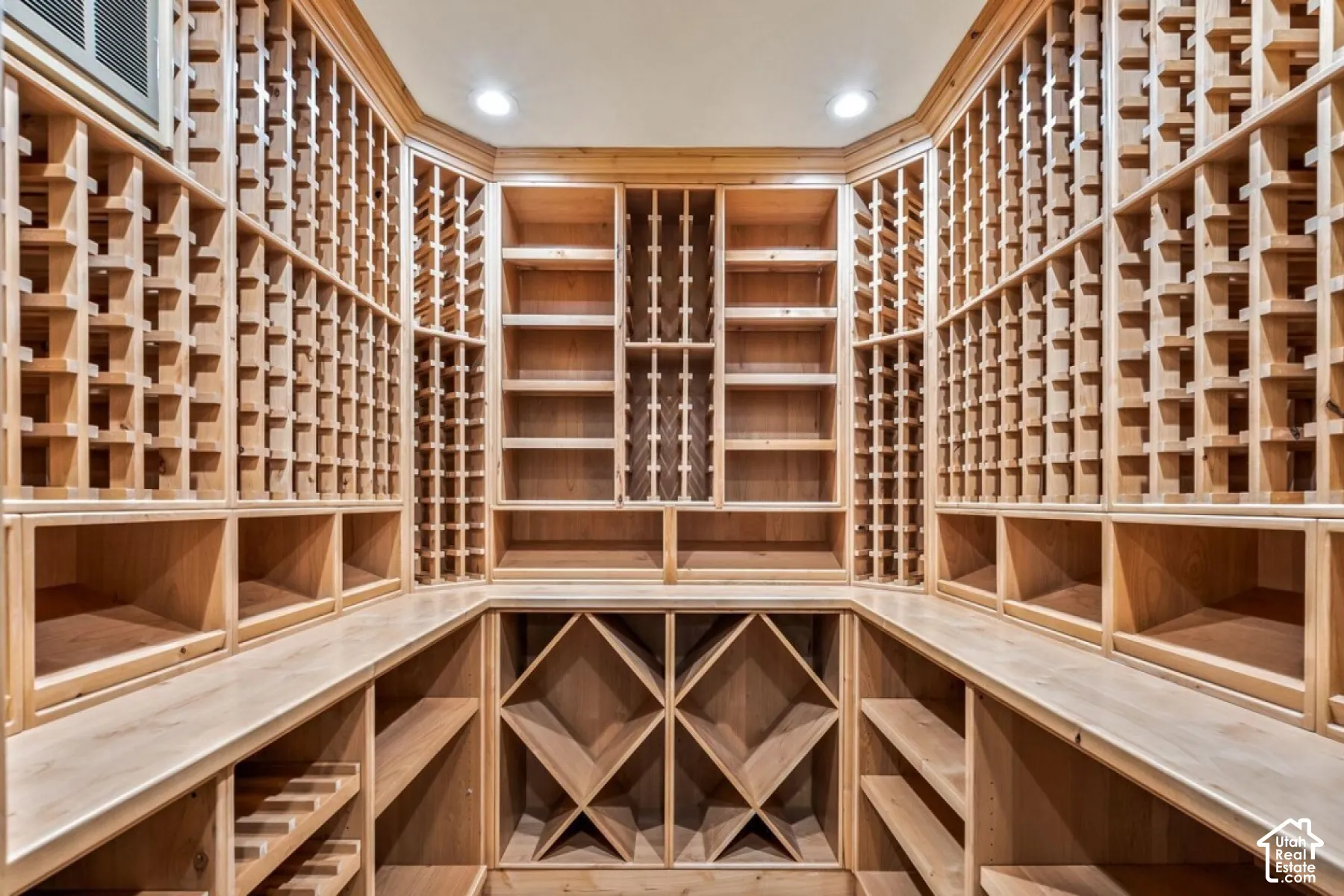 Custom built-in wood wine storage with individual bottle racks, bin storage, display shelving, and recessed lighting