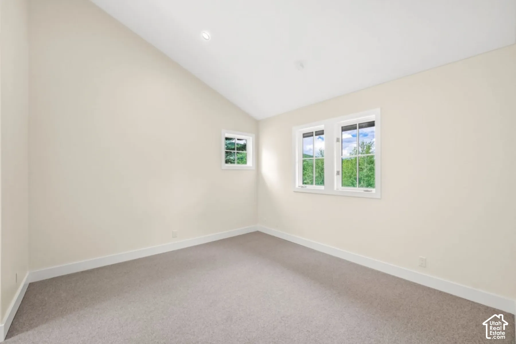 Vaulted ceiling, recessed lighting, neutral wall color, white window trim, and carpeted flooring