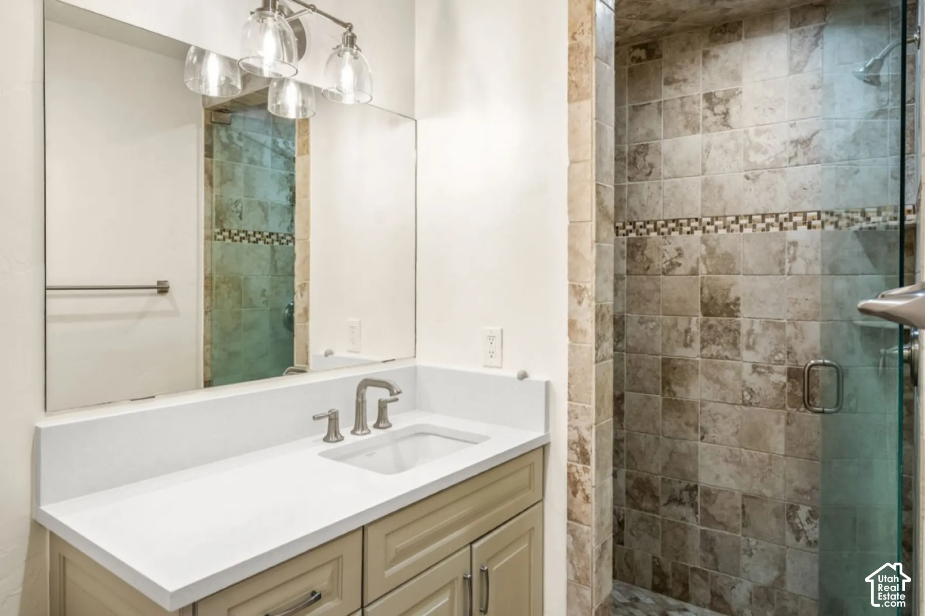 Vanity with a white countertop and undermount sink, brushed nickel faucet, and wood-finish cabinetry