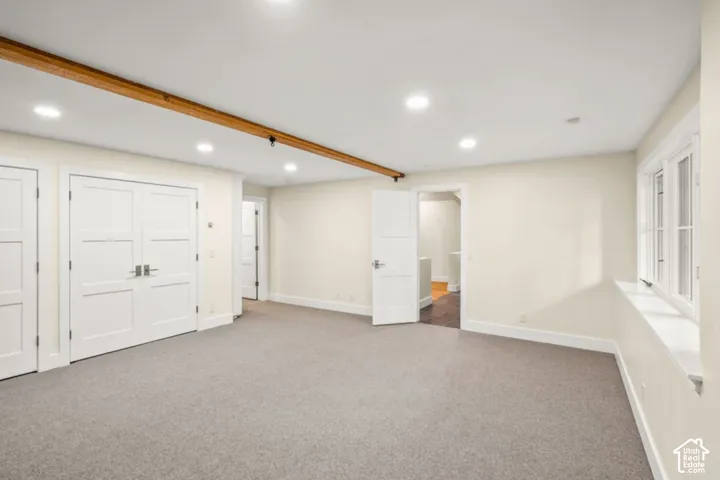 Recessed lighting, wood beam ceiling accent, neutral wall paint, gray carpet flooring, multiple panel doors
