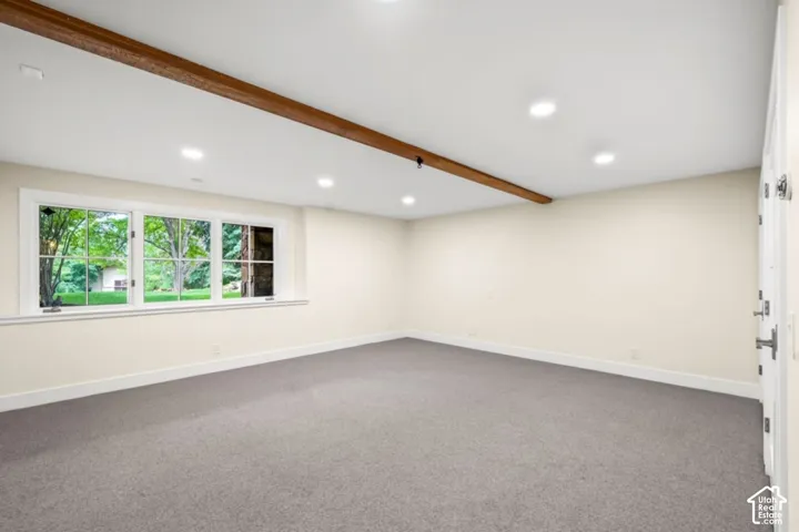 Recessed lighting, wood-beam ceiling accent, wall-to-wall carpeting, white trim, and a multi-pane window
