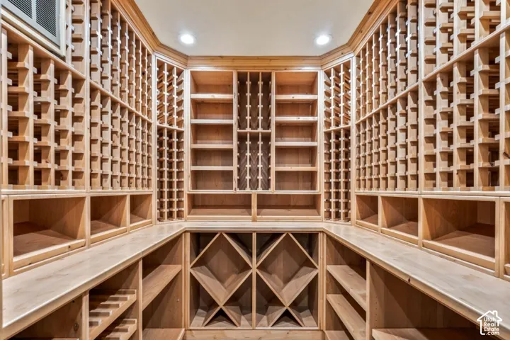 Custom built-in wood wine storage with individual bottle racks, bin storage, display shelving, and recessed lighting