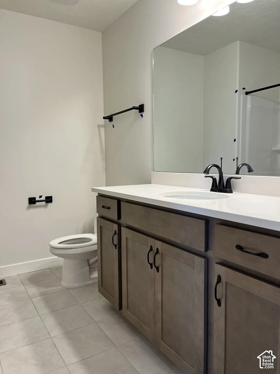 Wood-finish vanity with white countertop, undermount sink, and matte black faucet