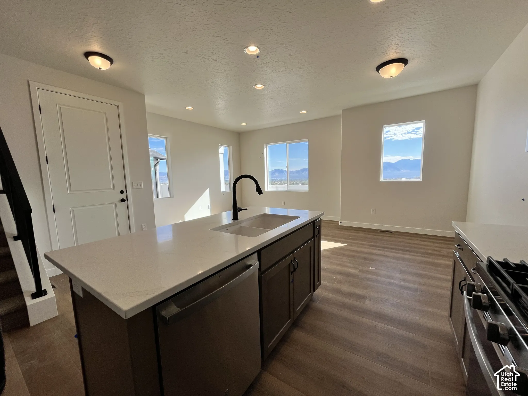 Kitchen island with an undermount double-basin sink, black gooseneck faucet, and integrated stainless steel dishwasher