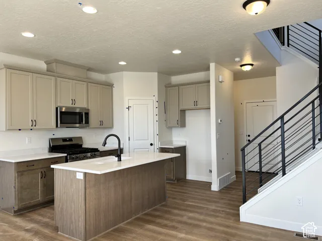 Kitchen featuring a central island, white countertops, stainless steel appliances, and wood-finish flooring