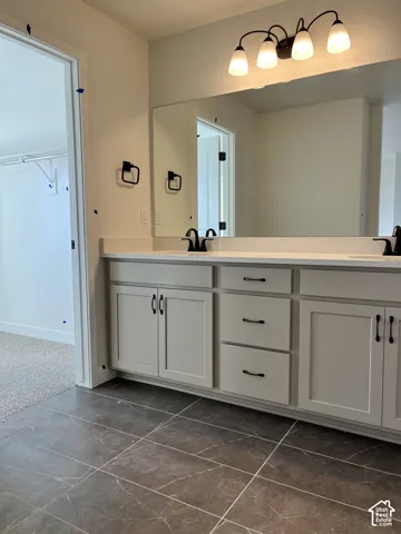 Dual vanity with matte black fixtures, light-toned cabinetry, and a full-width mirror