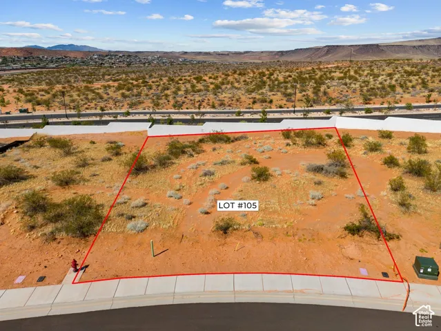 Desert landscape lot with a paved street frontage, concrete sidewalk, and utilities installed
