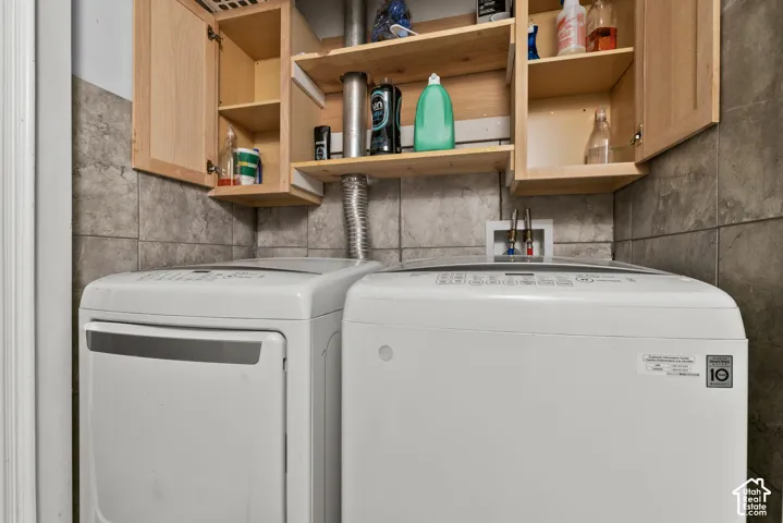 Tile wall covering, wooden upper cabinetry, and a utility hookup