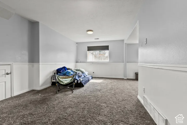 Carpeted room with a window, white wainscoting, and a flush-mount ceiling light
