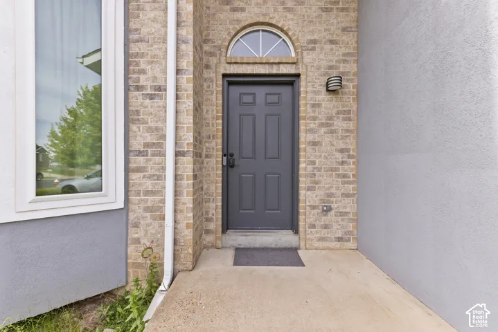 Brick exterior with a paneled entry door, arched transom window, and an exterior wall light fixture