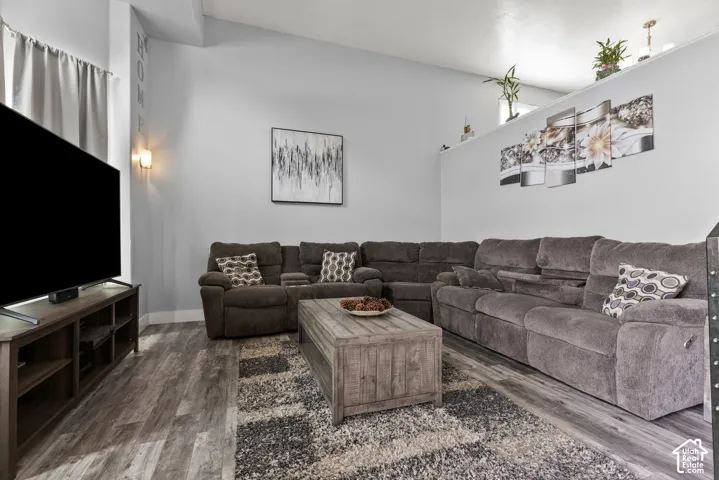 Spacious living area featuring vaulted ceilings, wood-finish flooring, and built-in wall sconces