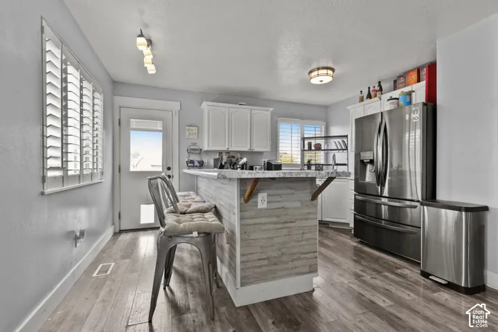 Kitchen featuring wood-finish flooring, white cabinetry, and stainless steel refrigerator