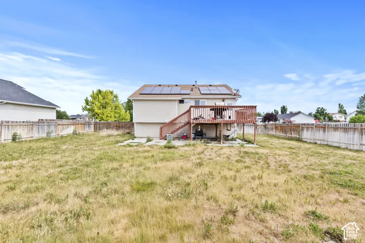 Expansive fenced backyard with a wood deck and solar panels
