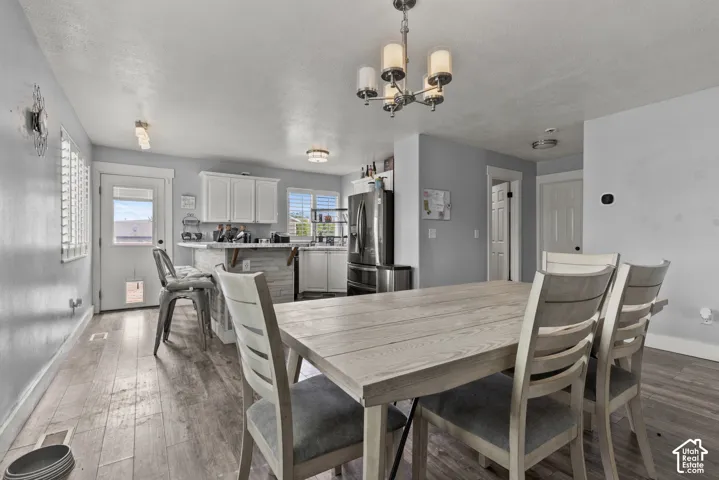 Wood-finish flooring throughout, white cabinetry, stainless steel appliances, and a chandelier with glass shades